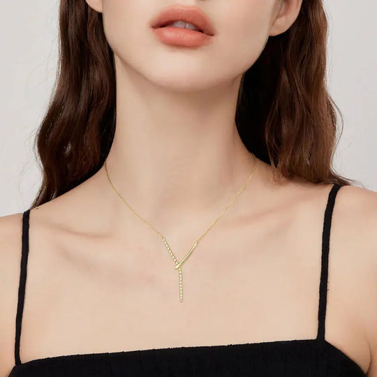 Woman wearing a gold necklace against a neutral background