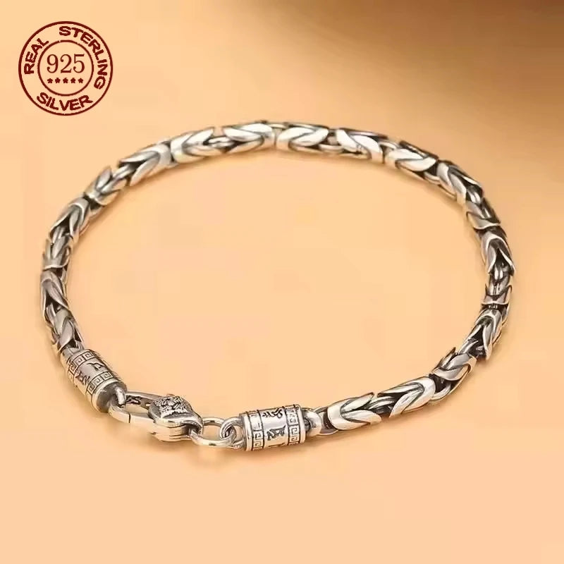 Silver bracelet with braided design on a beige background, featuring 'Real Sterling Silver' stamp.
