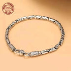 Silver bracelet with braided design on a beige background, featuring 'Real Sterling Silver' stamp.