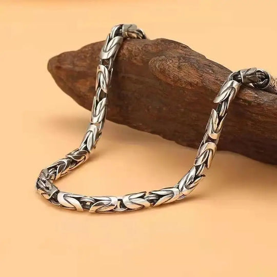 Silver chain bracelet on a wooden surface with a warm background